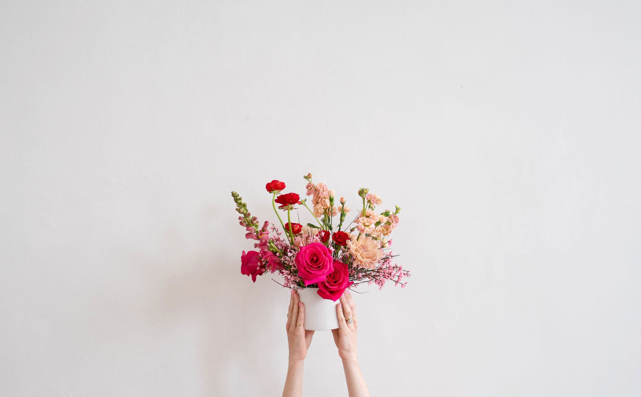 Hands holding a Native Poppy Valentine’s Day arrangement