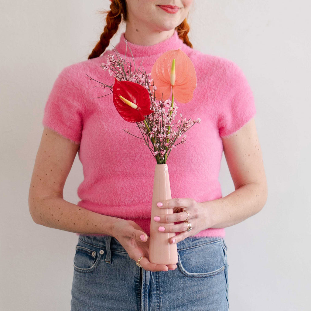 Woman holding a pink vase of anthurium flowers