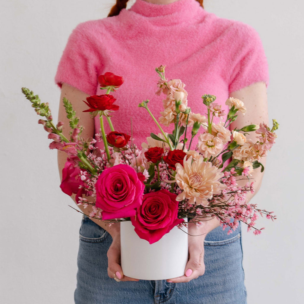 A woman in a pink shirt holding a flower arrangement