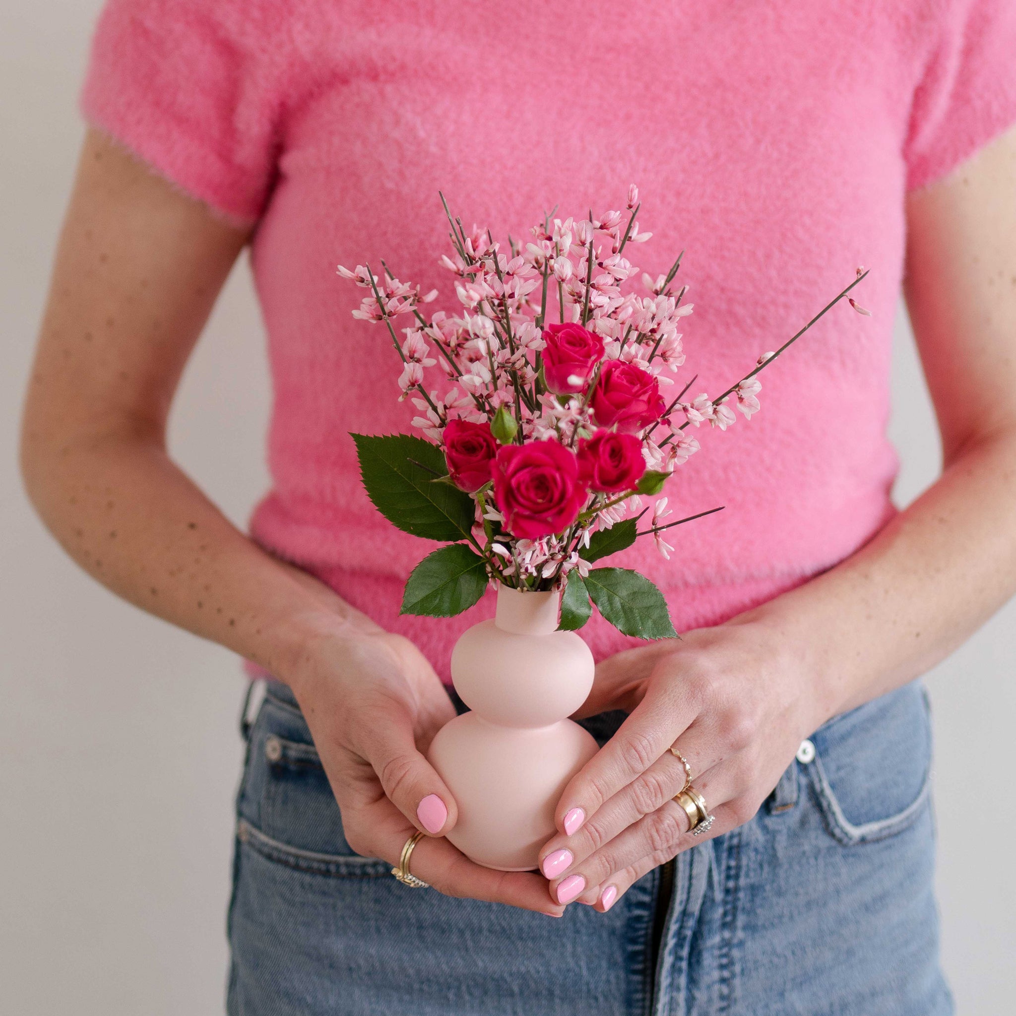 Woman holding a small pink Valentine's Day flower arrangement