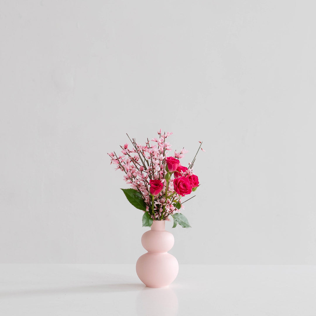 A pink vase of small roses