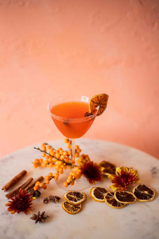 An orange cocktail with dried orange peels and flowers
