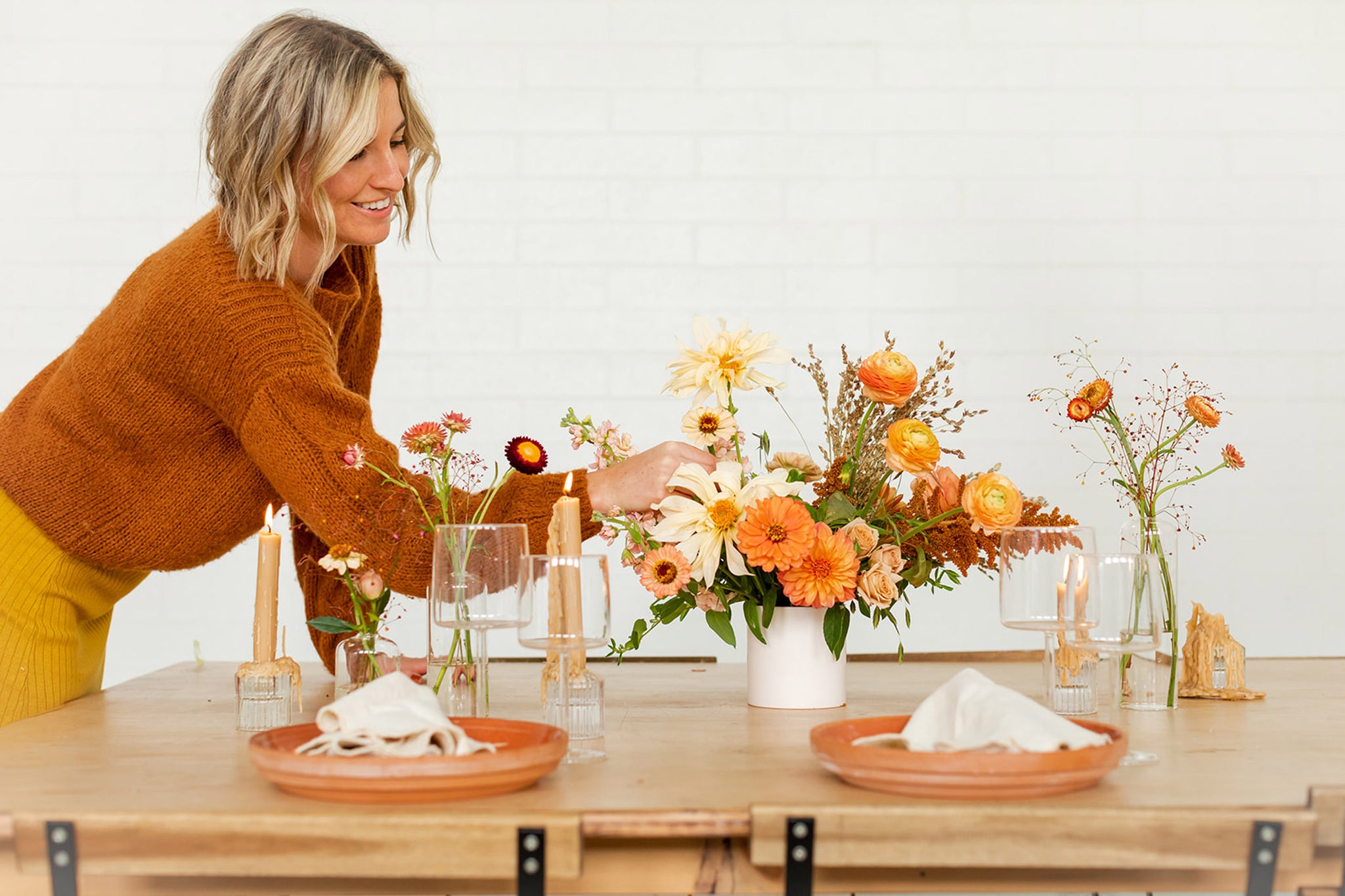 Woman adjusting Thanksgiving flowers in a vase on a table