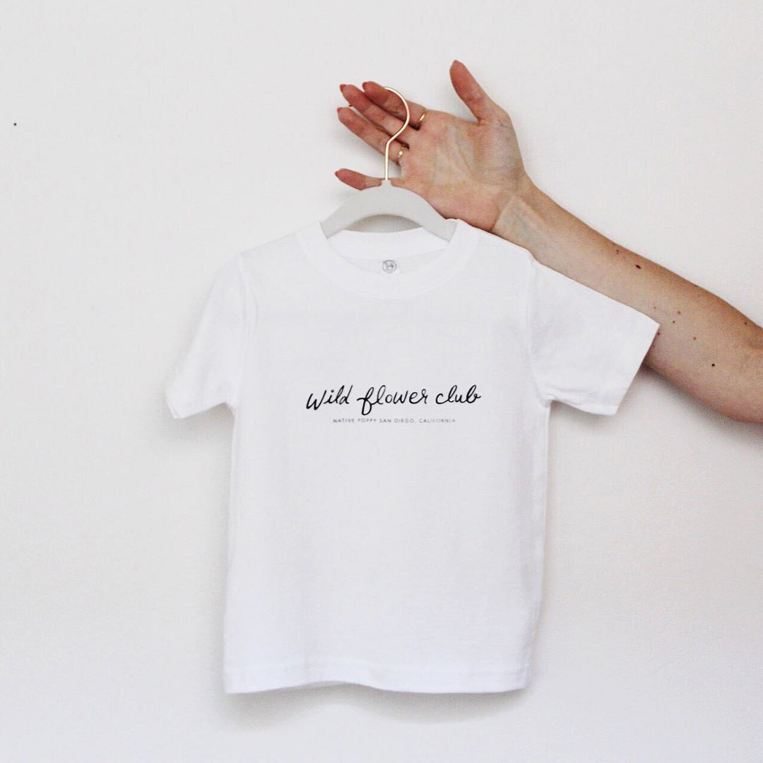 Hand holding Wild Flower Club toddler shirt