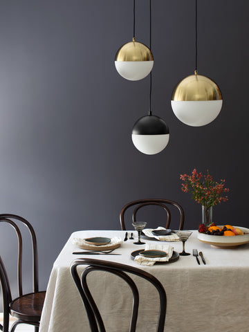 Celeste pendant lights in brass and black hanging over a dining table
