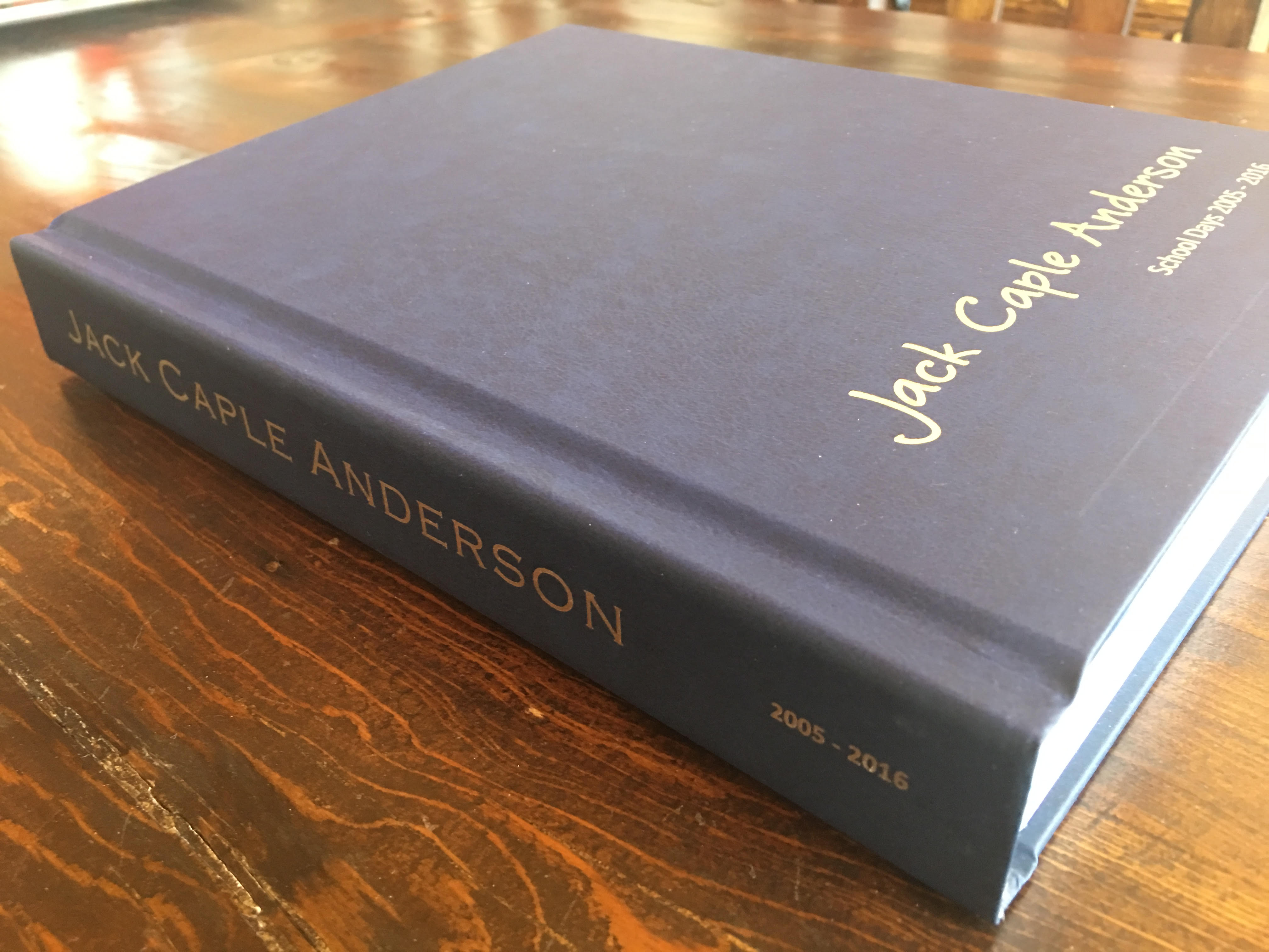 Blue hardcover book titled 'Jack Caple Anderson' on a wooden surface.