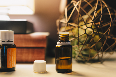 Two brown bottles of essential oil with white caps on a table 