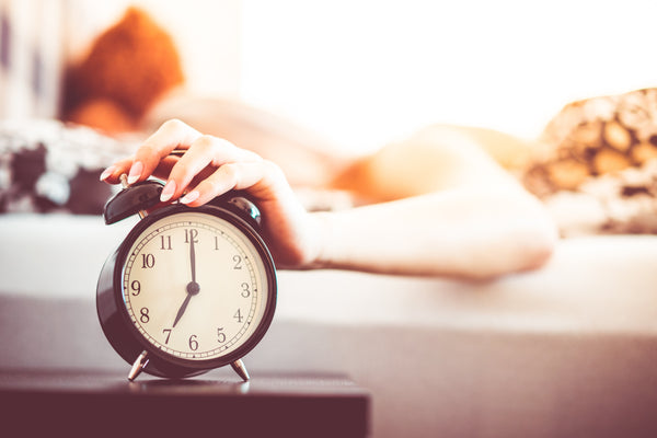 Woman on bed turn off alarm clock