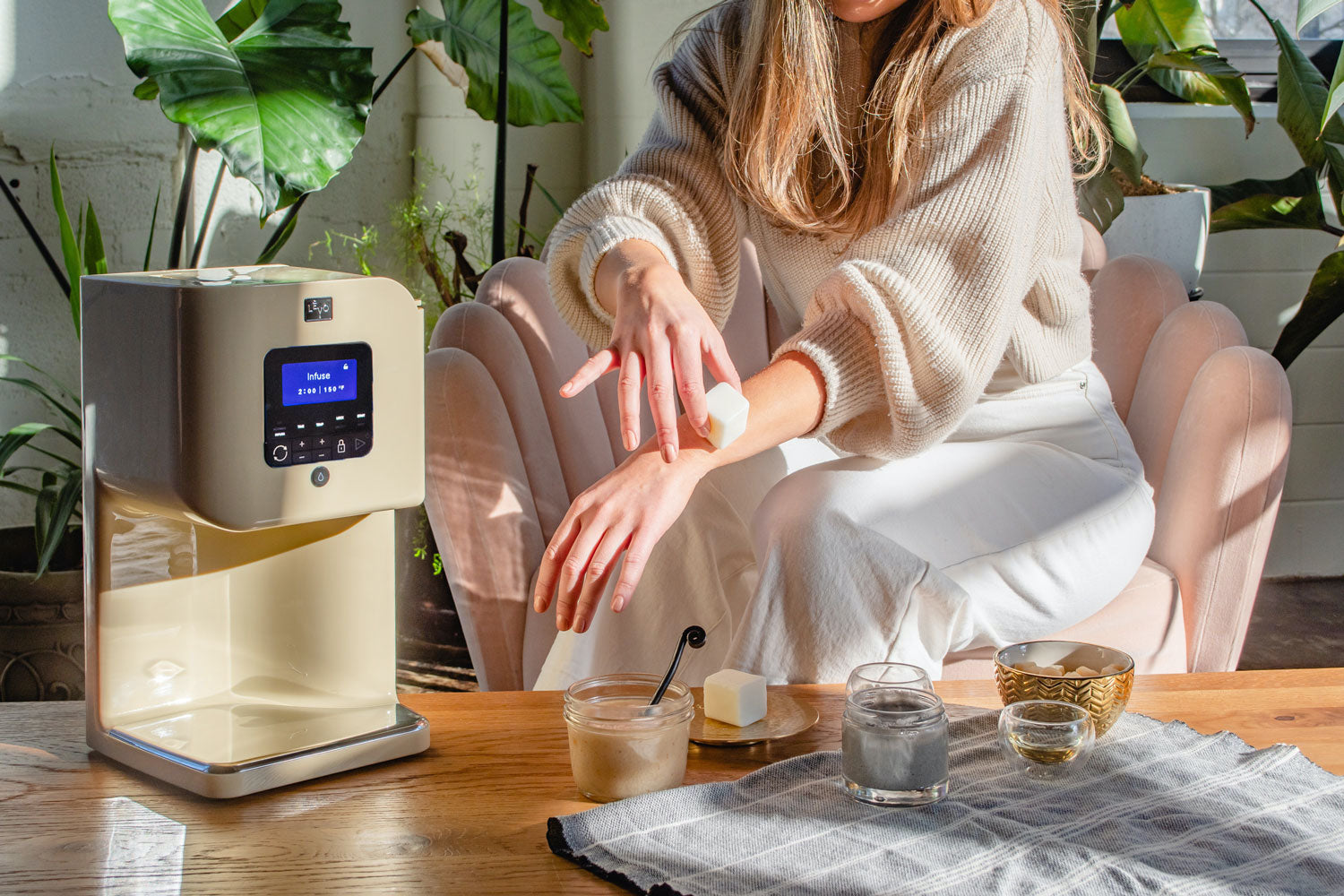 Image of a woman sitting next to a Honey Cream LEVO II machine with her DIY skincare routine.