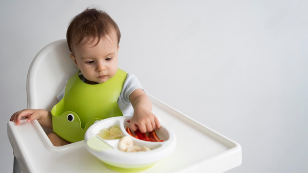 Toddler eating on a high chair with a portion size meal