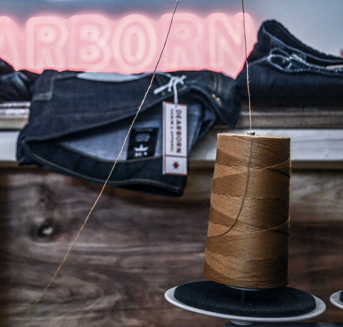 Jeans on counter behind spool of our signature golden thread