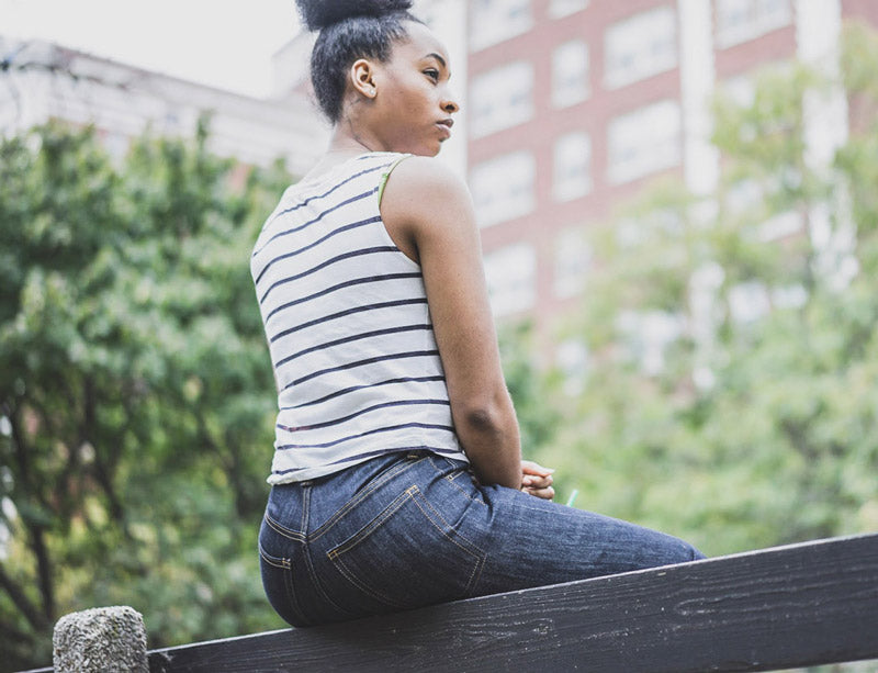 Melody comfortable sitting on a fence in her Dearborn Denims