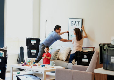 man and children hanging paintings on wall