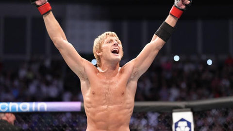 An image of an MMA fighter with his arms raised to the ceiling in a victory stance.