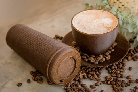 Another image of the travel container and cup and saucer with beans spilling over.