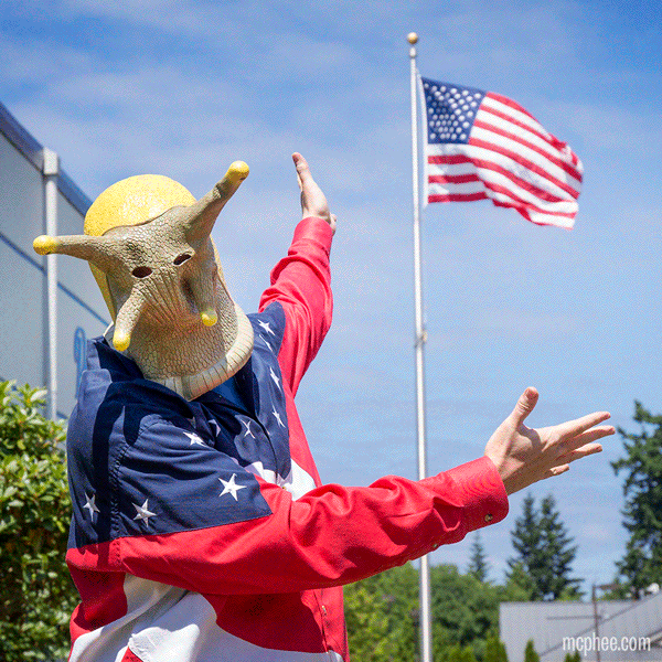 A person in a Banana Slug Mask and a patriotic shirt in front of an American flag.