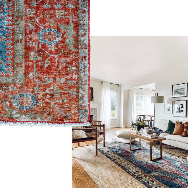 a bright living room with lots of natural light shining through an open window. An antique rug layered over a jute is the focal point of this room. A large armchair and sofa is positioned around the rug, with a small wooden coffee table in the centre.