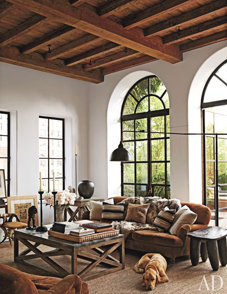 Monochrome living room with large curved windows and a sleeping dog - Belongs to writer Brad Goldfarb as featured in Architectural Digest