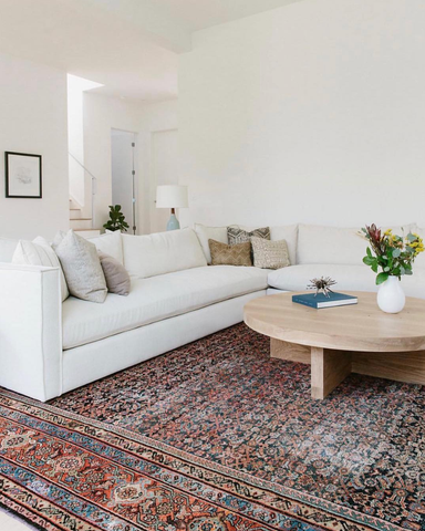 a large antique rug is the centrepiece, and a large white corner sofa sits on top