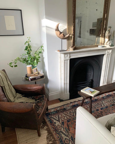 a living room with a leather club chair and an antique rug