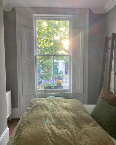 Light streams through a Victorian window into a bedroom