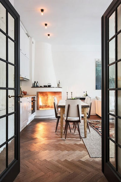 bright kitchen with glass doors, high ceilings, wooden floors and a large dining table and stove