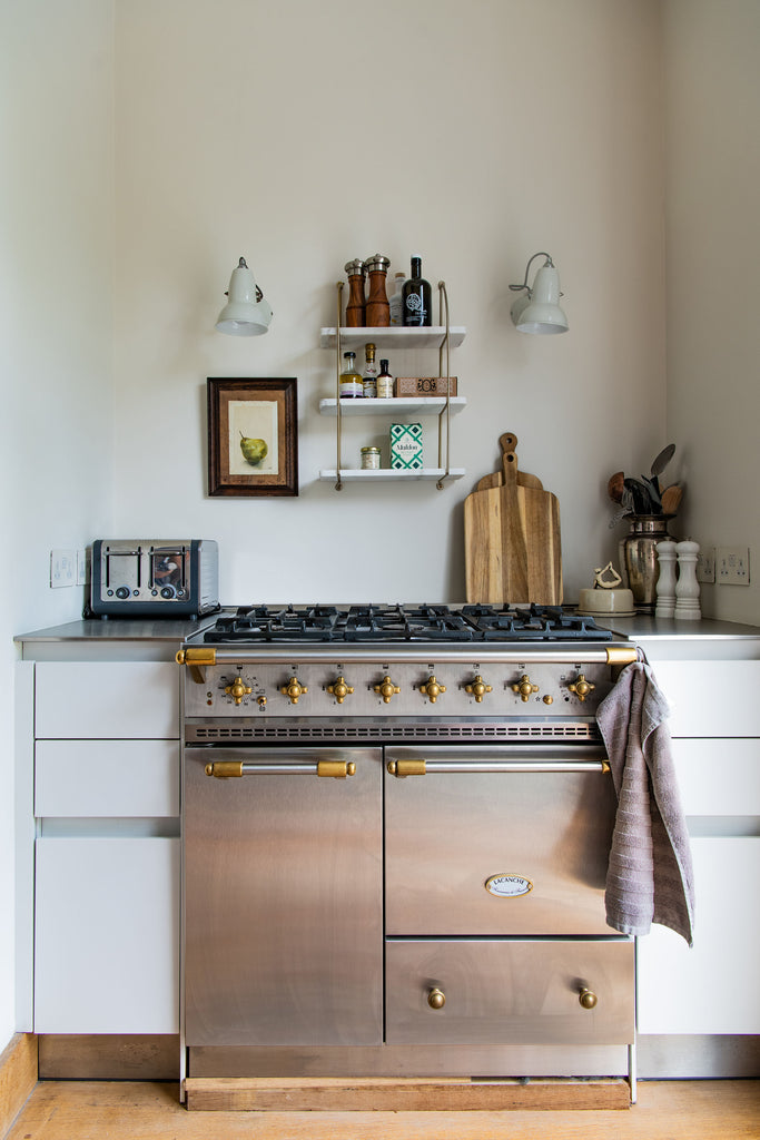 large gas stove with small marble shelves above 