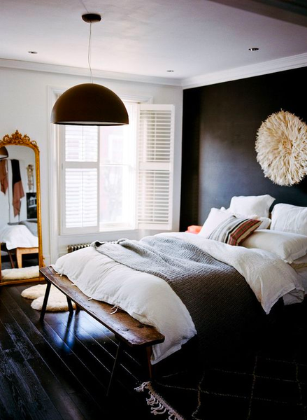 a black Berber rug lies beside a large bed.