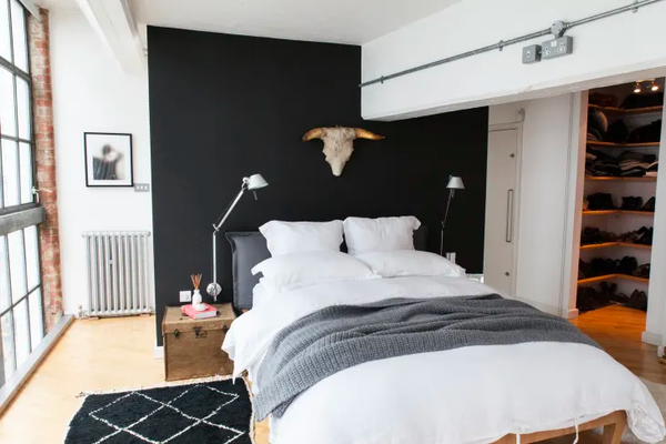 a black Berber rug beside a large bed with lush white linen bedding