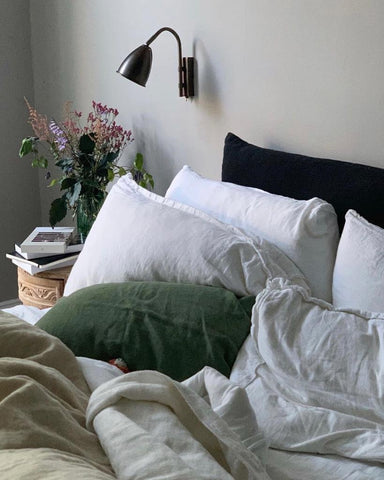 an unmade bed with natural linen bedding