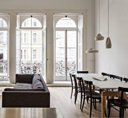 a large Victorian apartment with high ceilings, large windows and a big dining table