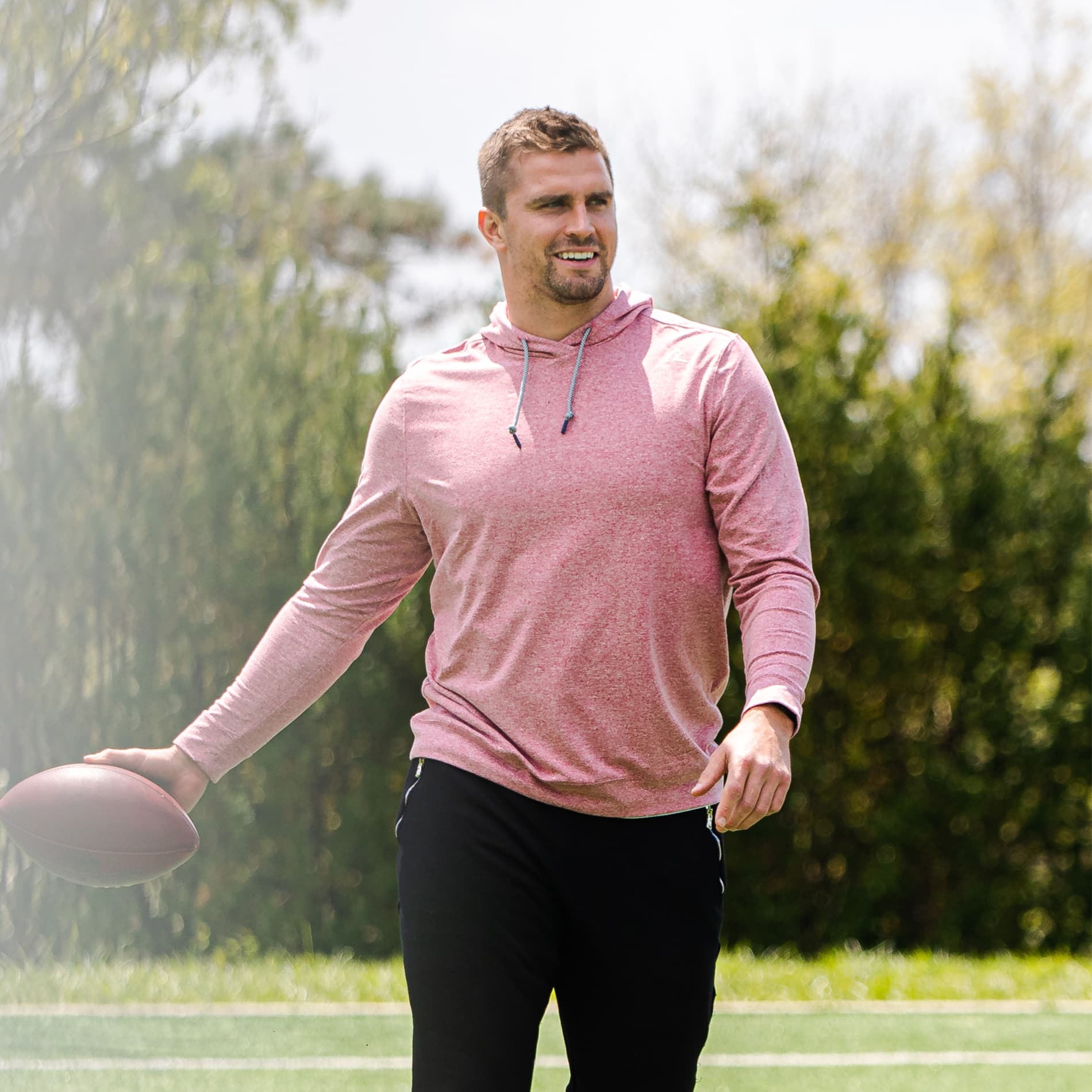 Sam Hubbard professional football player holding a football wearing the Red Card Hoody