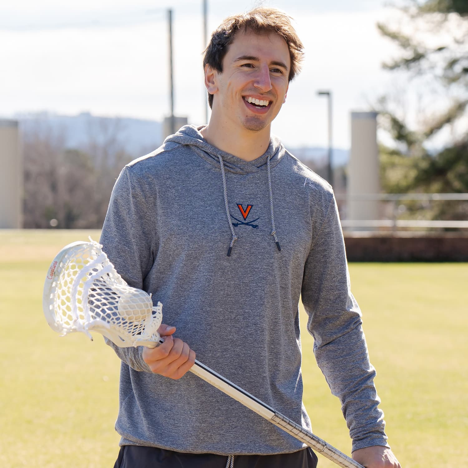 Connor Shellenberger holding a lacrosse stick wearing The Lawn Hoodie