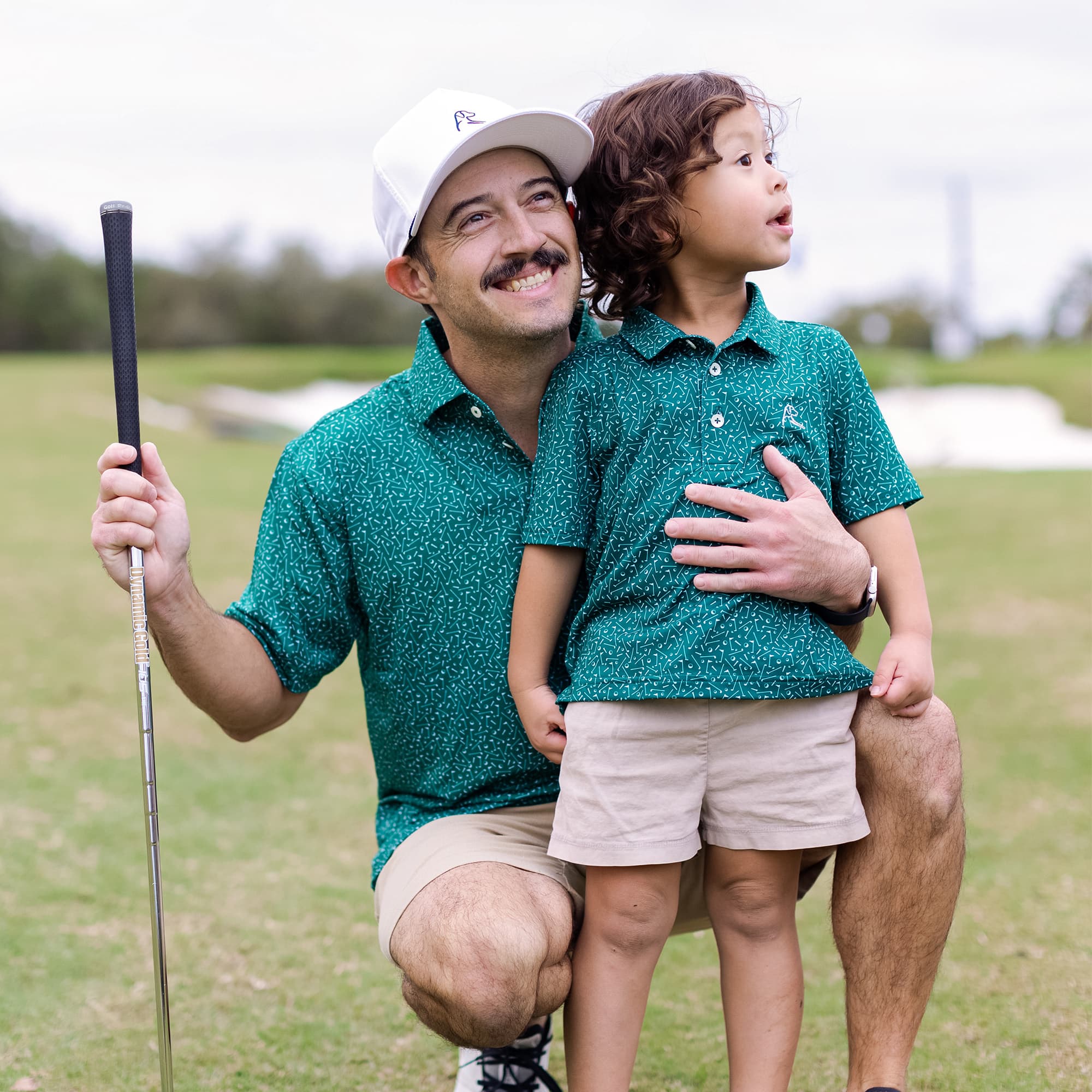 Dad with his kid playing golf. Both wearing Rhoback apparel.