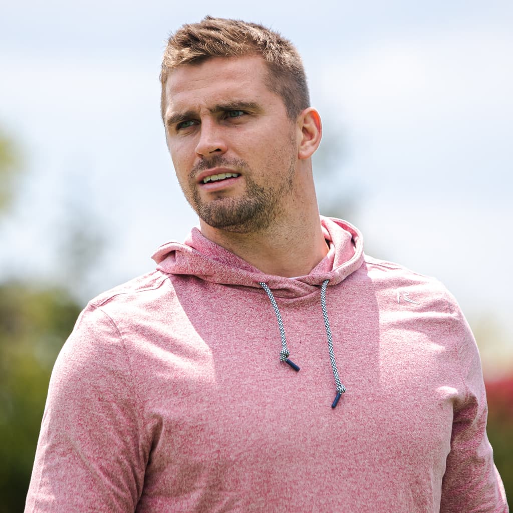 Sam Hubbard holding a football wearing the Big Foot polo