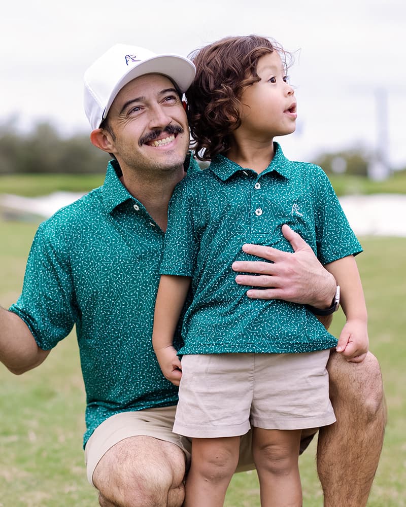Dad hugging his son while holding a golf club and both wearing Rhoback Polos.