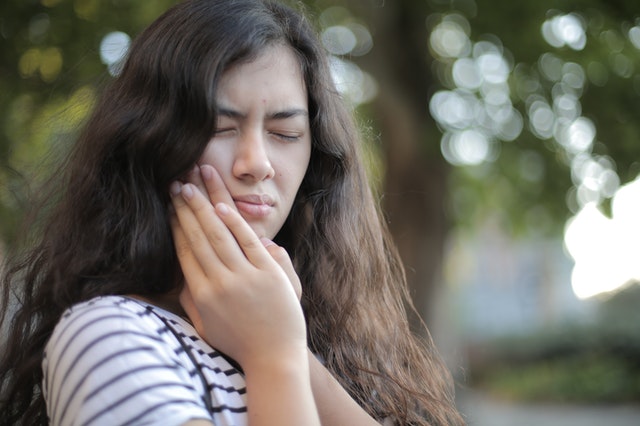Woman dealing with toothache symptoms due to swollen gums 