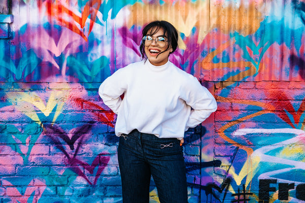 Woman with white teeth standing in front of multicolored wall