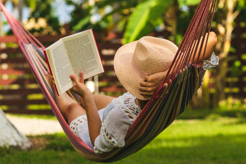 woman relaxing and reading a book on a hammock