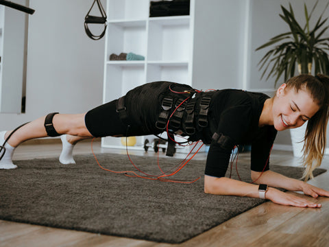 Girl doing plank with EMS Electrostimulation body suit for body firming