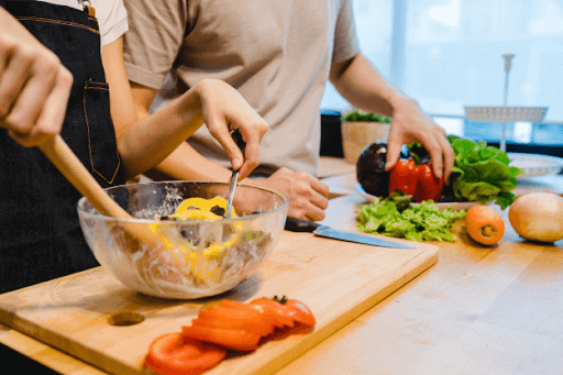 two people making salad and fish for dinner