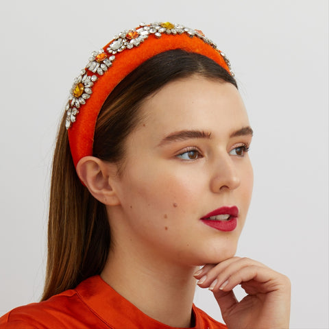 woman wearing a bright orange jewelled headband looking off into the distance