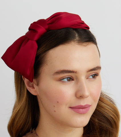 Red bow fascinator headband worn by woman