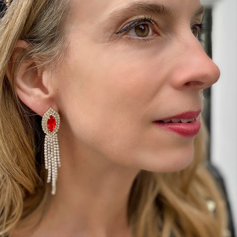 woman wearing dangly diamante earrings with red stone in the middle of them