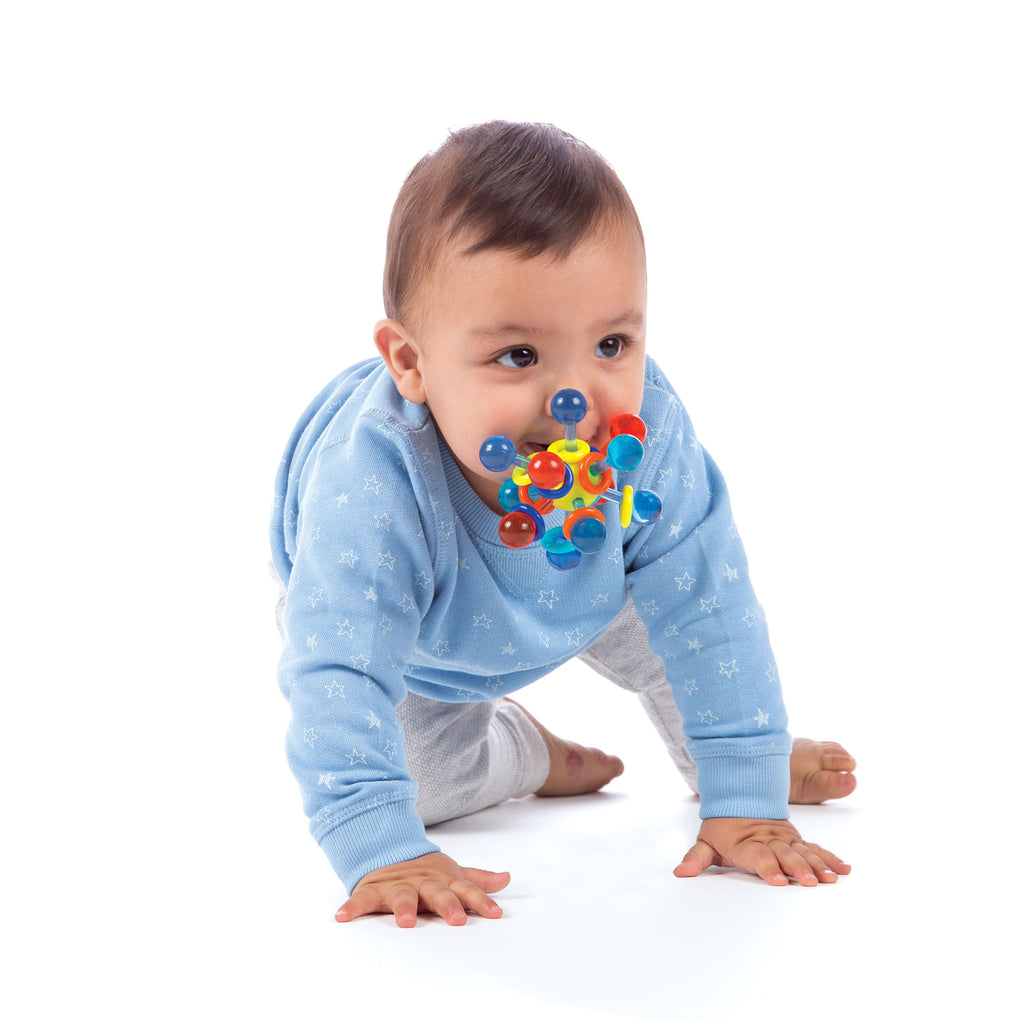 Ten-month old boy crawling on floor with a teether toy in his mouth. 