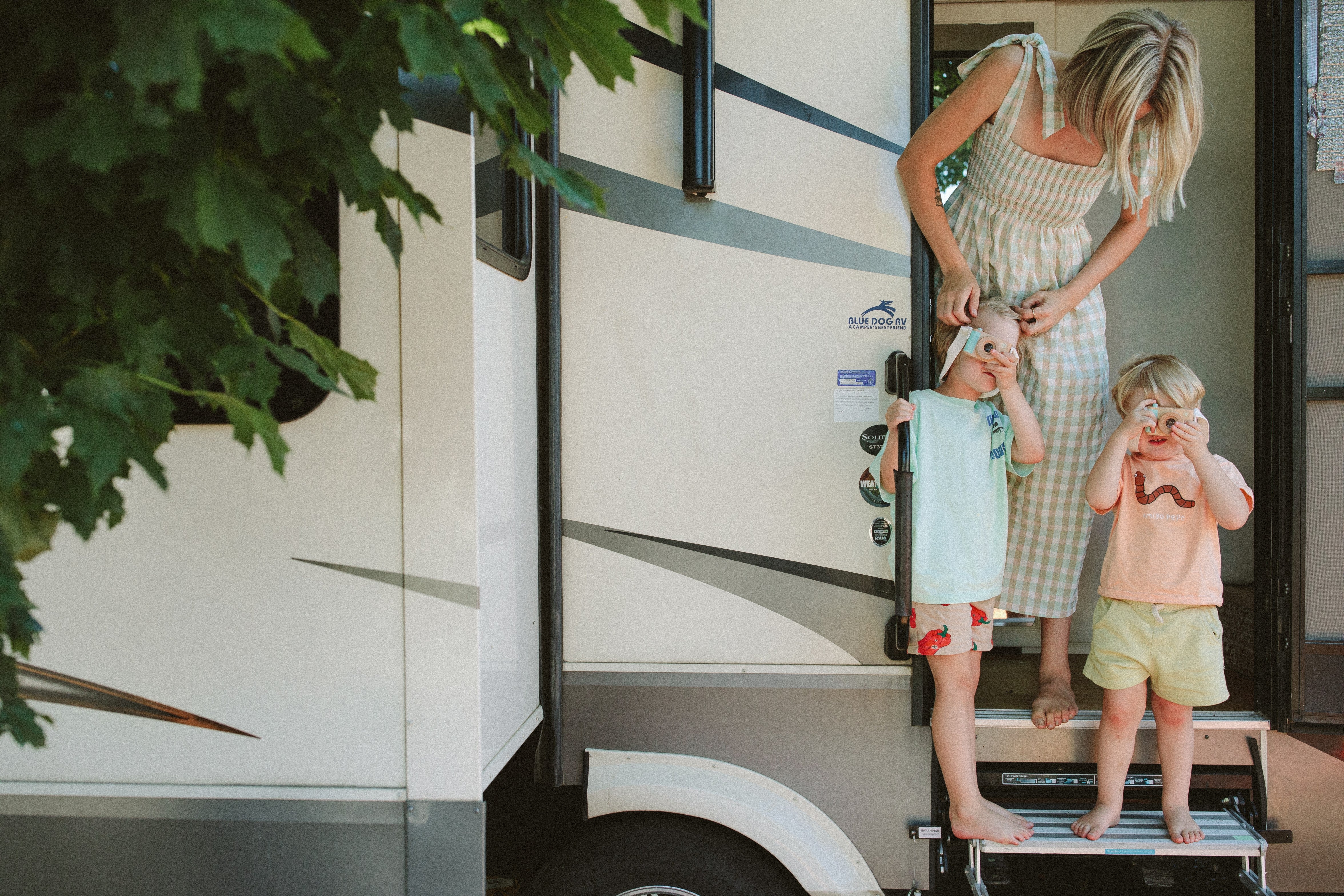 Paige Jones and family outside their RV with kids using Manhattan Toy wood cameras.