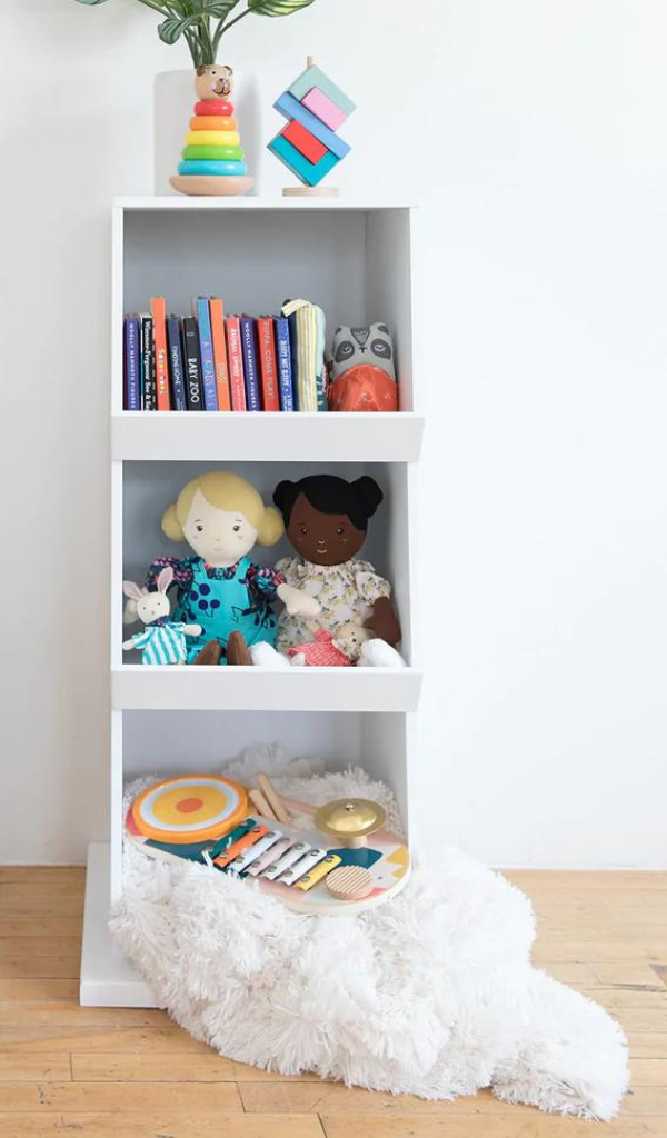 Toy storage shelving with books, dolls, stacking toys and musical toys placed in the cubbies and shelves.