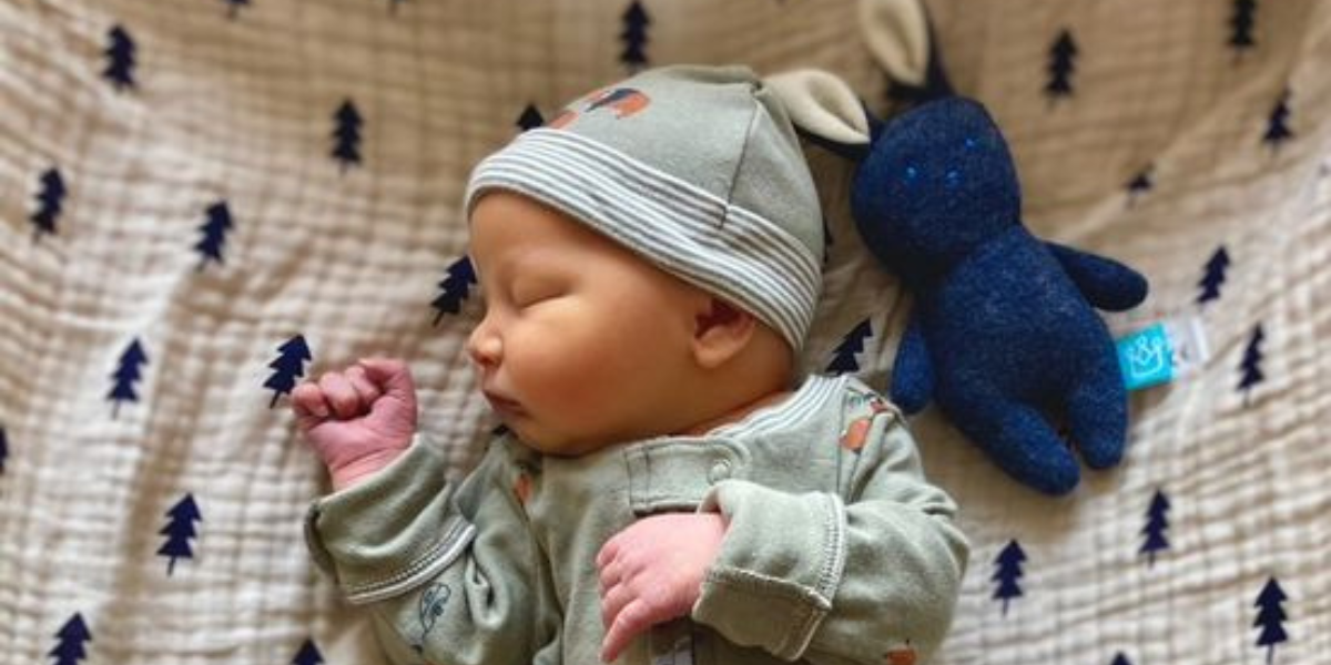 Baby sleeping next to blue bunny rattle