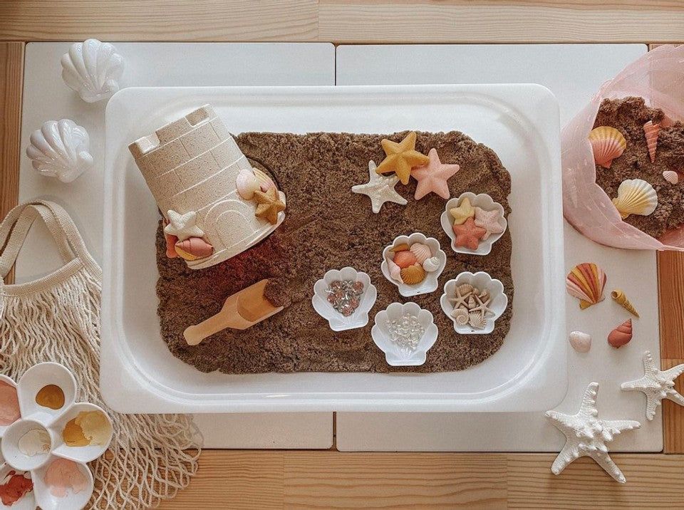 Art/sensory play table for crafting and messy play activities. Shown with sand and sea shells for sensory play. Photo credit to Instagram user @theheinrichhouse.