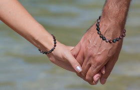 couple holding hands wearing spiritual healing bracelets